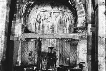 Kircheninnenraum mit halbrunder Apsis, davor ein gemusterter Vorhang