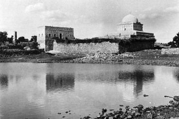 Klosteranlage mit Kuppelbau am Ufer eines Gewässers