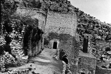 Ruinenanlage mit Bogengängen und aufragendem Mauerturm