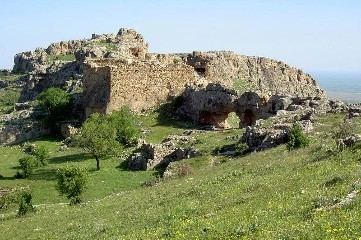 Ruine auf einem Felsrücken über grüner Frühlingslandschaft