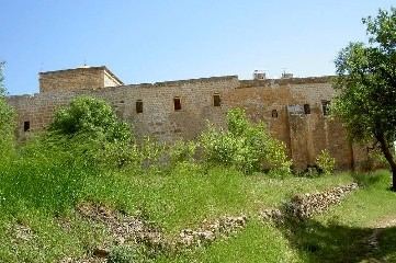 Lange Klostermauer mit Fensterreihe hinter einer Wiese