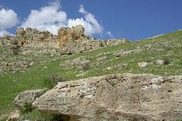 Mauerreste auf einer Felskuppe unter Wolkenhimmel